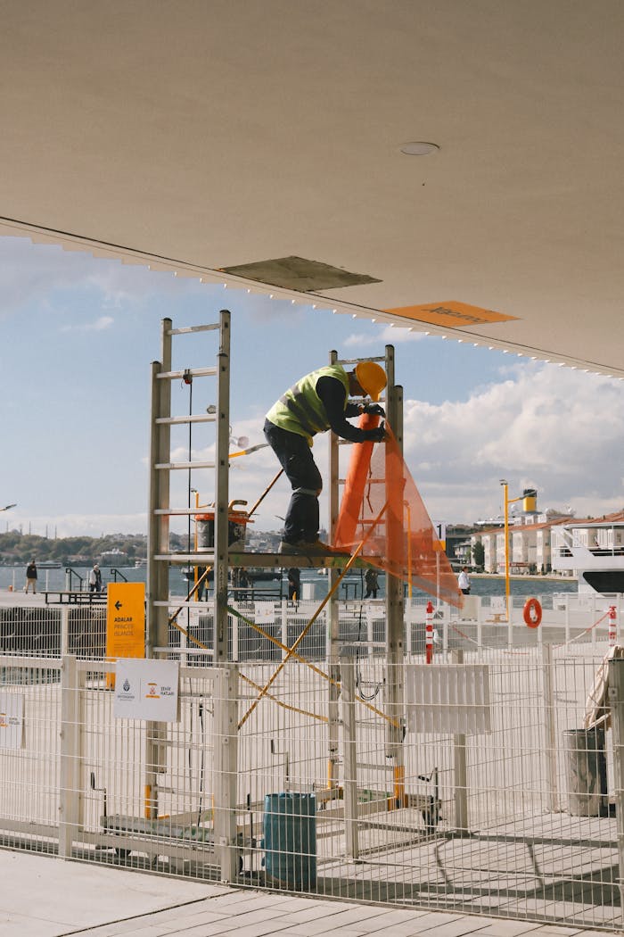 services-04 Construction worker securing safety net on scaffold at outdoor site.