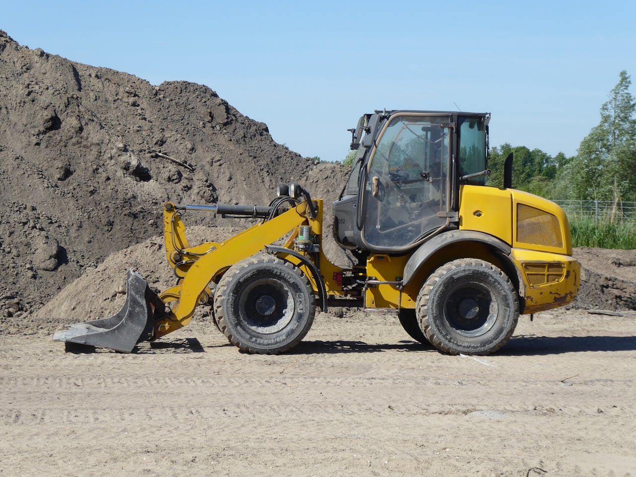 Crafting Captivating Headlines: Your awesome post title goes here Side view of a yellow loader at a construction site with dirt mounds.